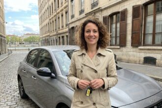 Femme tenant les clés d'une voiture de location devant un bâtiment lyonnais typique dans le quartier de la Presqu'île