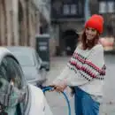 a woman in a red hat is pumping gas into a car