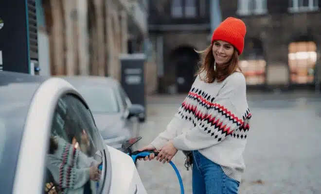 a woman in a red hat is pumping gas into a car