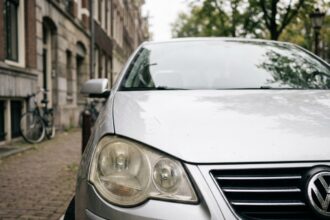 Gros plan sur le phare avant d'une Volkswagen Polo 5 garé en ville, optique légèrement jaunie avec condensation visible